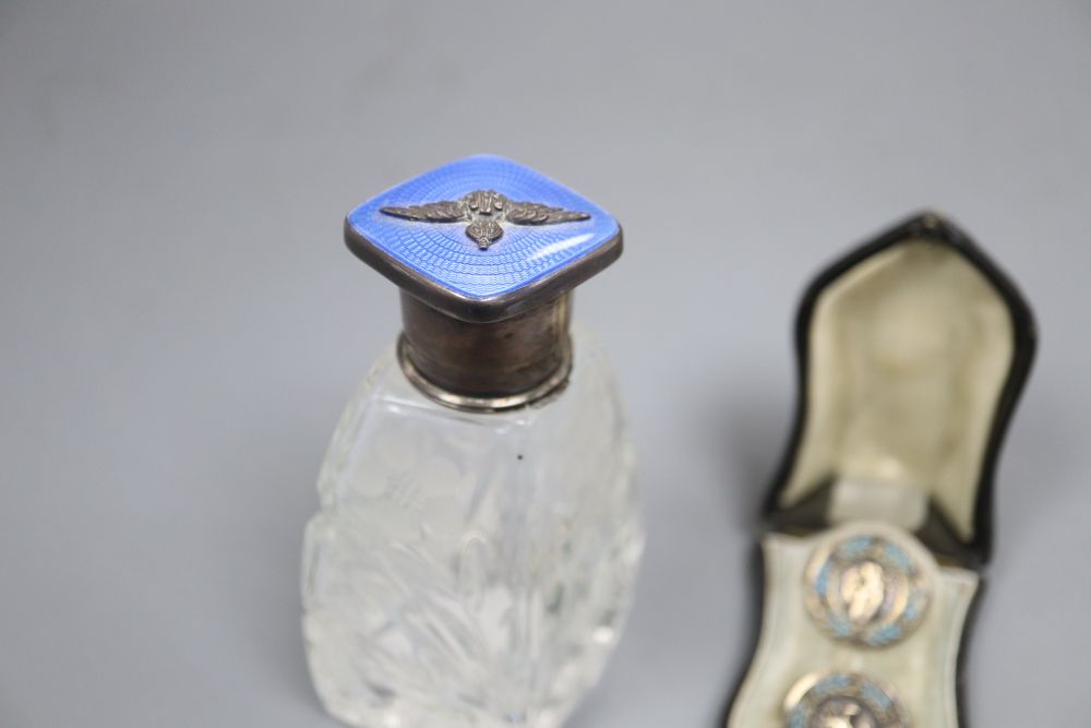 A cased pair of French white metal and enamel lapel buttons and a silver and enamel mounted glass scent bottle